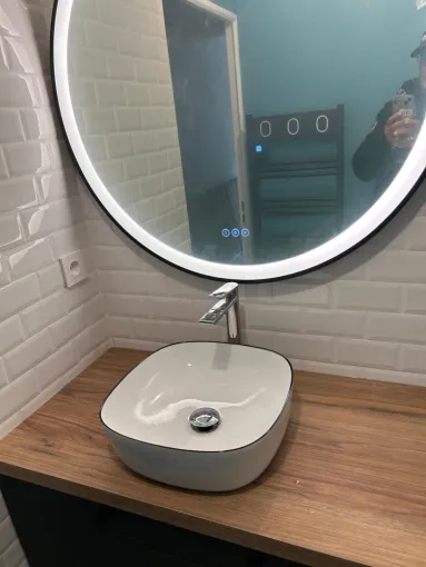 Support et Mobilier : Pose d'un plan de travail en chêne massif, traité en autoclave pour une résistance accrue à l'humidité. Installation d'une vasque à poser avec raccordements d'évacuation dissimulés pour une finition nette.  Plomberie : Raccordement d'un mitigeur chromé haut, assurant le bon débit et l'étanchéité au niveau de la perforation du plan de travail.  Revêtements et Électricité : Pose de faïence "métro" avec un soin particulier apporté aux coupes d'angle et à la régularité des joints pour l'ét