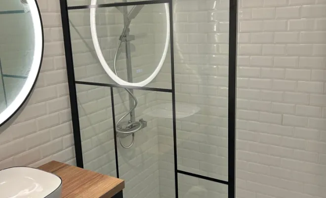 Étanchéité : Application d'une étanchéité sous carrelage sur toute la zone de la douche (murs et sol). Pose de carrelage "métro" sur l'ensemble des parois.  Plomberie : Installation d'un receveur de douche encastré pour un accès "de plain-pied", nécessitant un traitement rigoureux de l'évacuation (bondonne à grand débit). Pose et raccordement de la colonne de douche avec robinetterie thermostatique et douchette à main.  Menuiserie et Sécurité : Installation de la paroi de douche en verre trempé avec cadre e